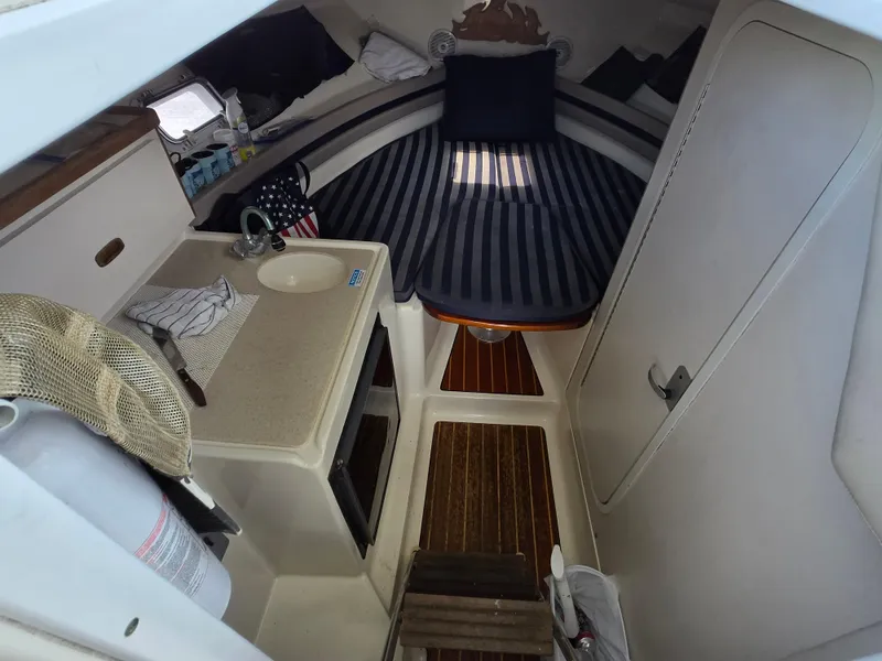 Slide: The Image of 2001 Pursuit 2860 Denali cabin interior with striped bedding and compact kitchenette. - 2