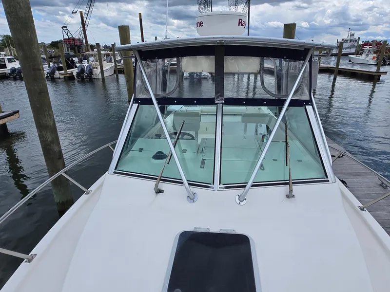 Slide: The Image of 2001 Pursuit 2860 Denali boat docked at marina, showcasing windshield and deck. - 21