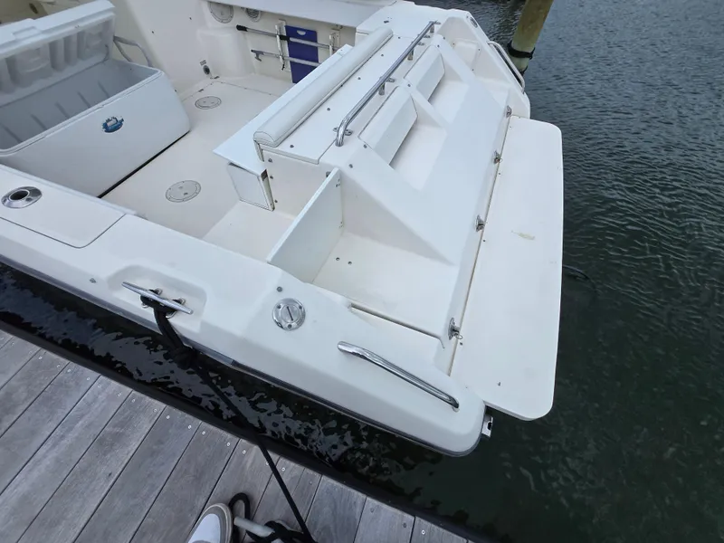 Slide: The Image of 2001 Pursuit 2860 Denali boat stern view, docked, showcasing spacious deck and storage compartments. - 23