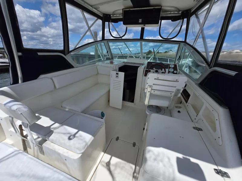 Slide: The Image of 2001 Pursuit 2860 Denali boat interior with seating and helm, under a clear blue sky. - 5