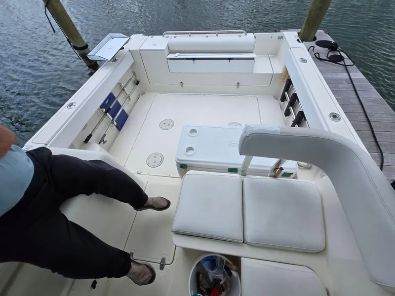 Slide: The Image of 2001 Pursuit 2860 Denali boat interior with seating and storage, docked by the water. - 8