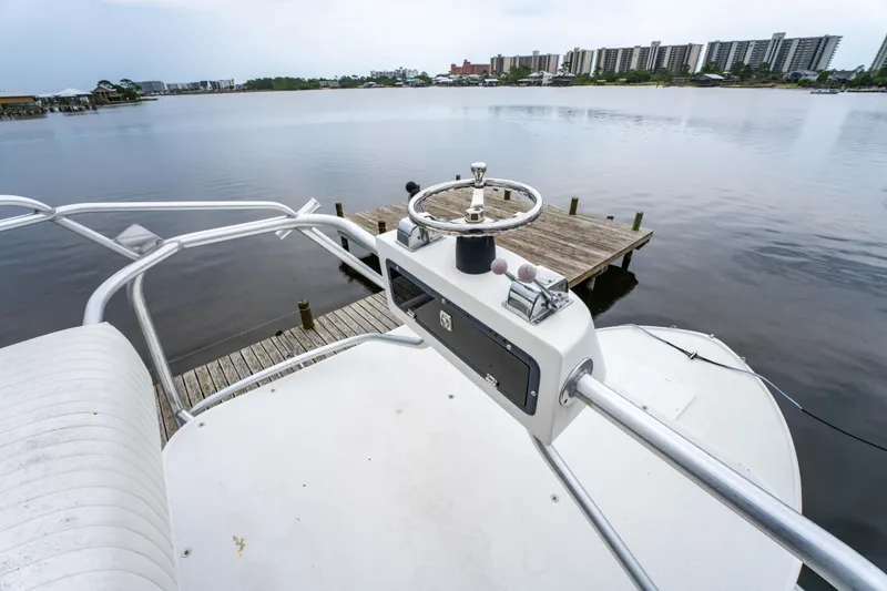 Slide: The Image of Helm of 1978 Topaz 28 boat overlooking calm waters and dock. - 17