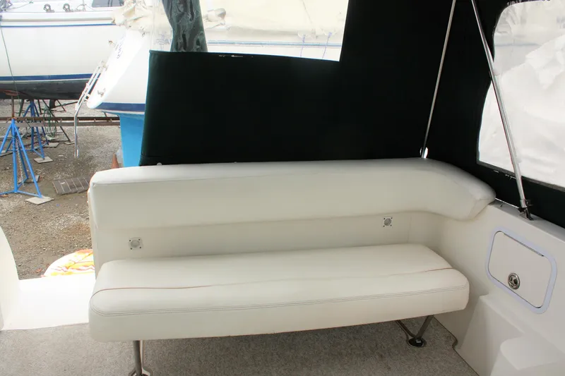 Slide: The Image of 2003 Sea Ray 260 Sundancer interior with white cushioned seating and black trim. - 11