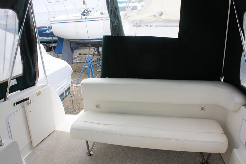 Slide: The Image of 2003 Sea Ray 260 Sundancer interior with white seating and outdoor view. - 12
