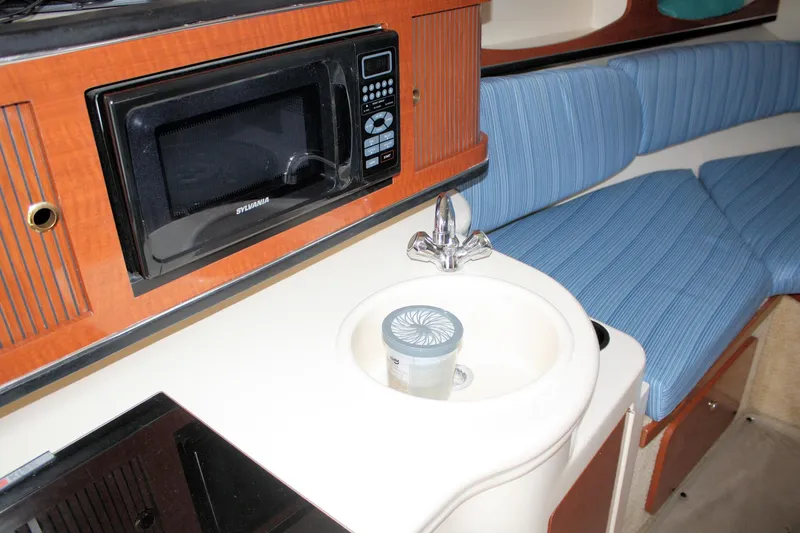 Slide: The Image of 2003 Sea Ray 260 Sundancer interior with microwave, sink, and blue seating. - 20