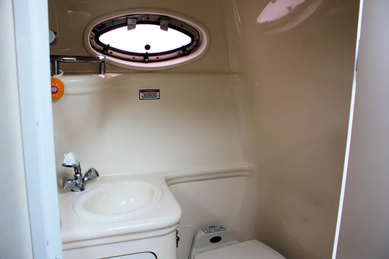 Slide: The Image of 2003 Sea Ray 260 Sundancer bathroom with sink, toilet, and porthole window. - 21