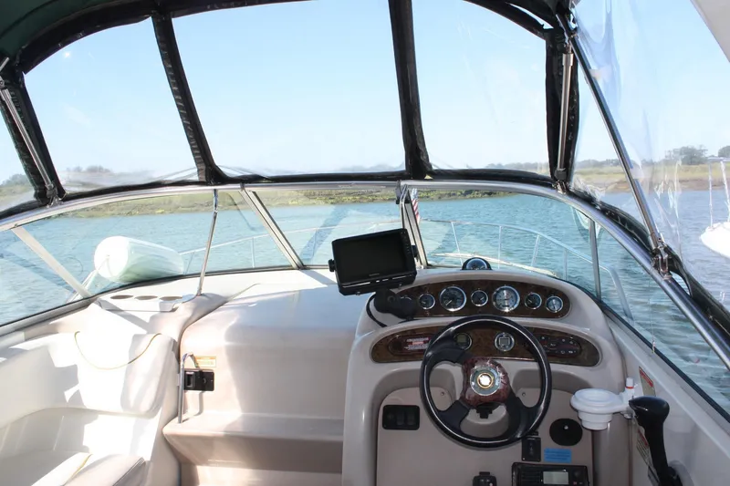 Slide: The Image of 2003 Sea Ray 260 Sundancer cockpit with steering wheel, dashboard, and water view. - 5