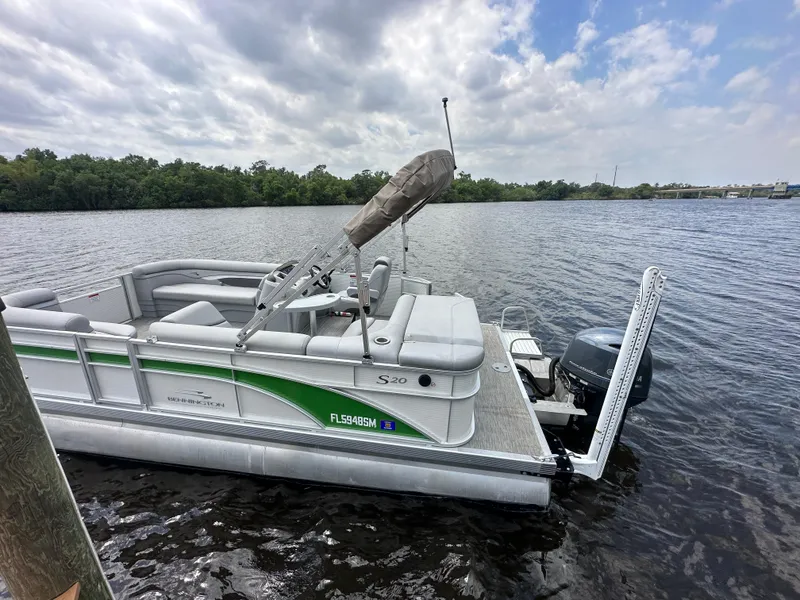 Slide: The Image of 2020 Bennington S 20 SLL pontoon boat on a calm river under cloudy skies. - 2