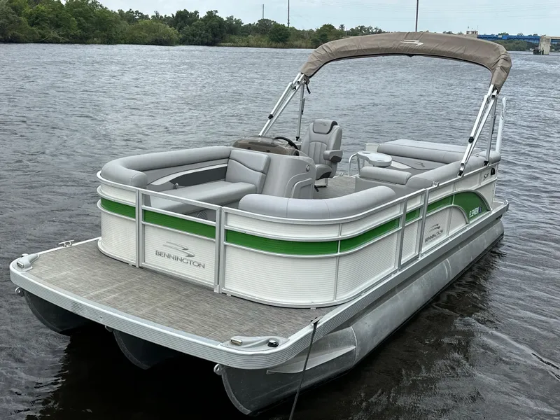Slide: The Image of 2020 Bennington S 20 SLL pontoon boat on calm water, featuring green accents and a canopy. - 3