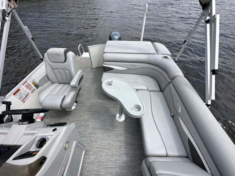 Slide: The Image of 2020 Bennington S 20 SLL pontoon boat interior with gray seating and table on the water. - 8