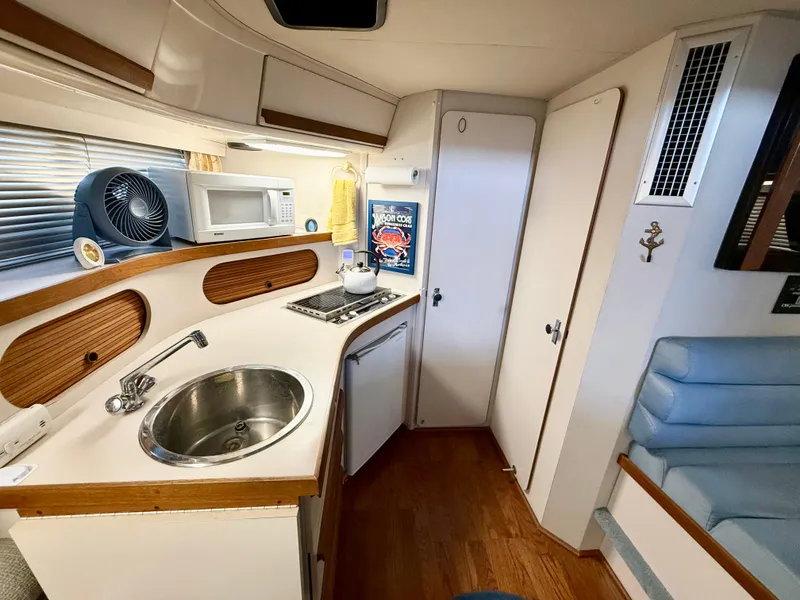 Slide: The Image of 1988 Carver Montego 3257 boat interior with kitchenette, sink, microwave, and seating area. - 34