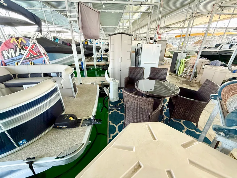 Slide: The Image of 2019 Bennington SX 25 Premium Swingback pontoon with outdoor seating and storage in a covered marina. - 24