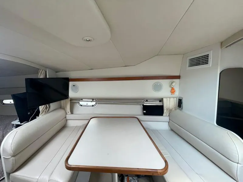 Slide: The Image of 1998 Cruisers Yachts 3375 Esprit interior with white seating, table, and mounted TV. - 13