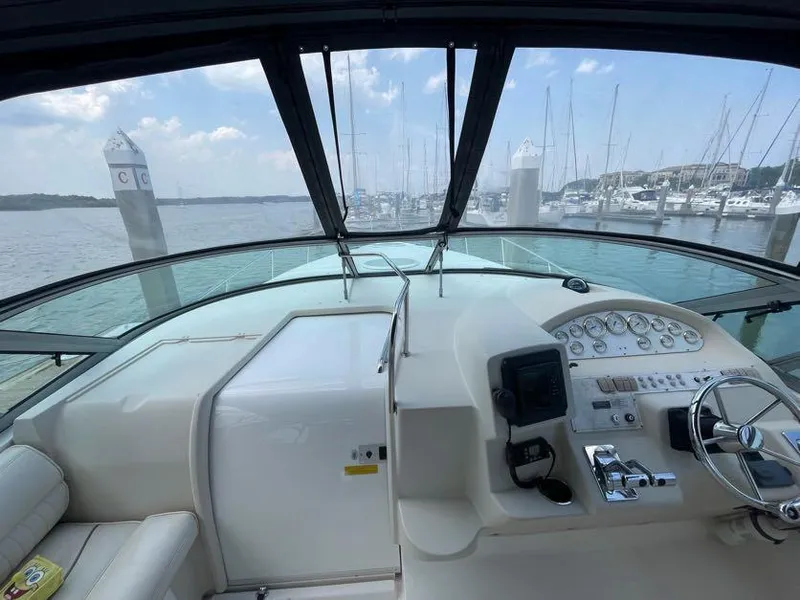 Slide: The Image of 1998 Cruisers Yachts 3375 Esprit helm with marina view, featuring steering wheel and control panel. - 9