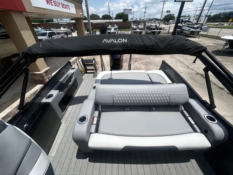 Slide: The Image of 2025 Avalon CAT VRB25T boat interior with gray seating and cup holders, displayed at a dealership. - 28
