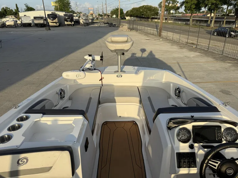 Slide: The Image of 2022 Hurricane SS205 boat interior with seating, steering console, and cup holders in a marina setting. - 12