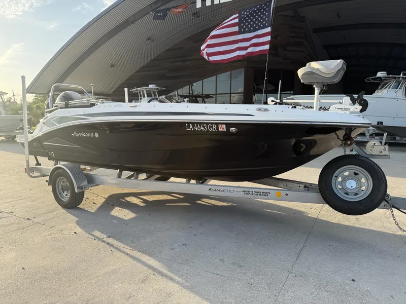 Slide: The Image of 2022 Hurricane SS205 boat on trailer, parked outdoors with American flag in background. - 2