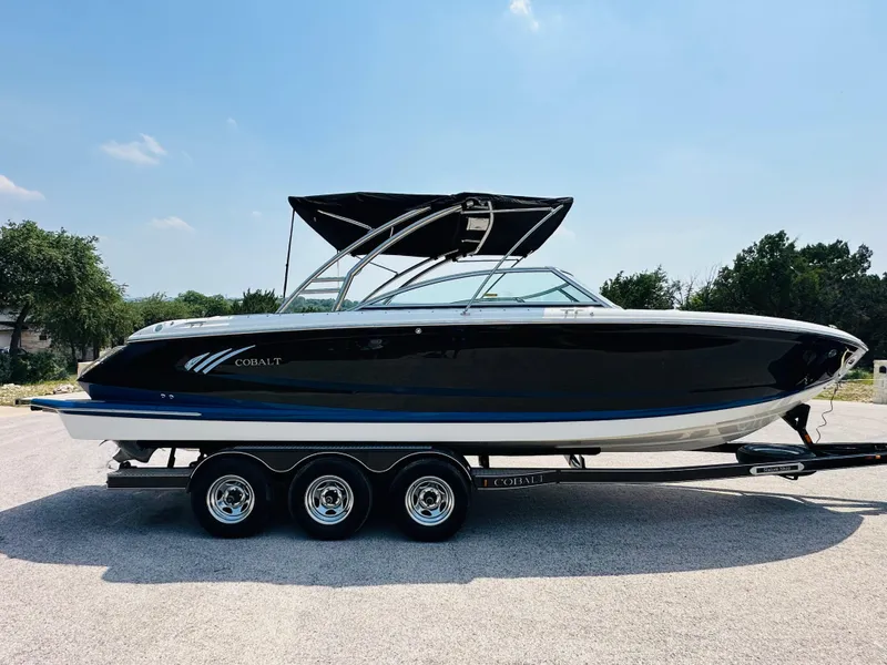 Slide: The Image of 2012 Cobalt A28 boat on trailer, black hull, sleek design, sunny day. - 14