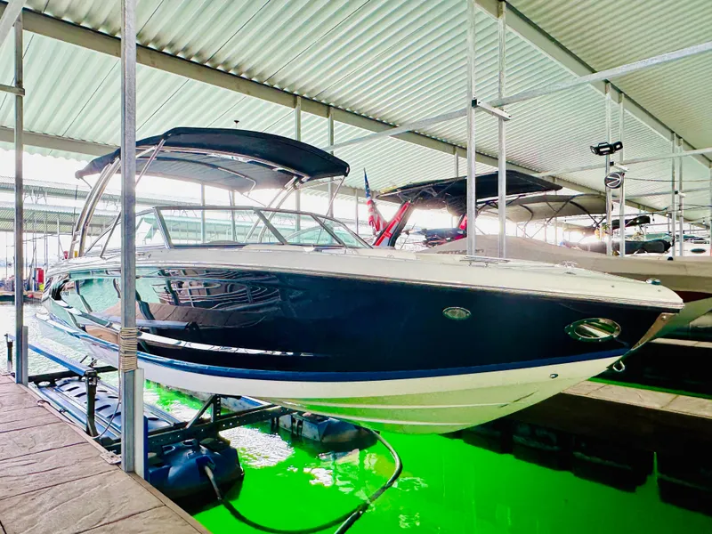 Slide: The Image of 2012 Cobalt A28 boat docked in a covered marina with green water reflection. - 18