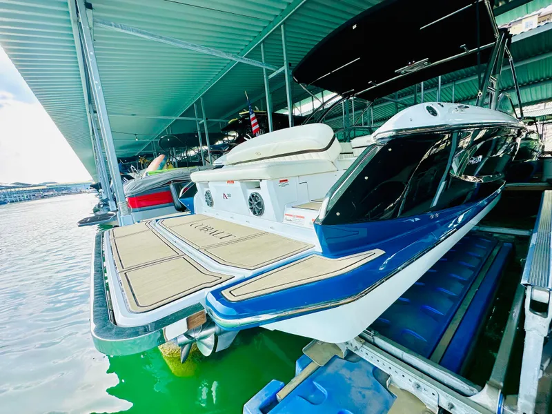Slide: The Image of 2012 Cobalt A28 boat docked in a marina under a covered structure. - 19