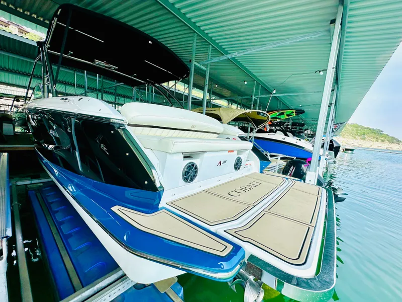 Slide: The Image of 2012 Cobalt A28 boat docked under a covered marina, featuring sleek design and spacious deck. - 22