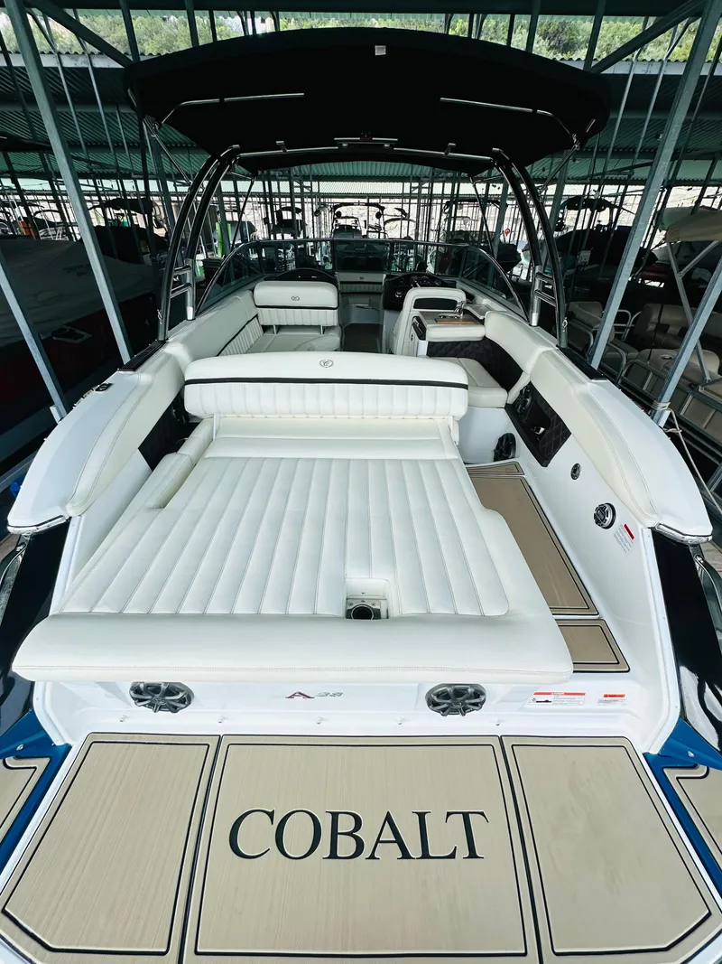 Slide: The Image of 2012 Cobalt A28 boat with spacious white seating and sleek design in a marina. - 28