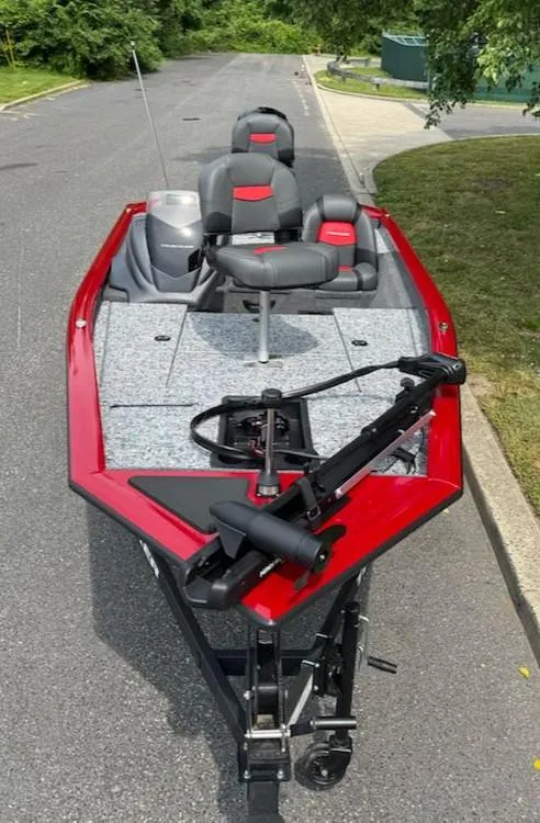 Slide: The Image of 2025 Tracker Pro Team 175 boat with red trim and gray seating on a road. - 6