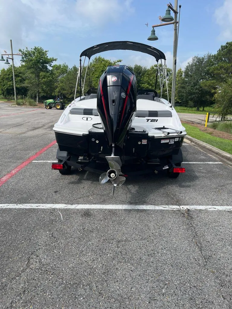 Slide: The Image of 2025 Tahoe T21 boat with outboard motor in parking lot, surrounded by trees. - 2