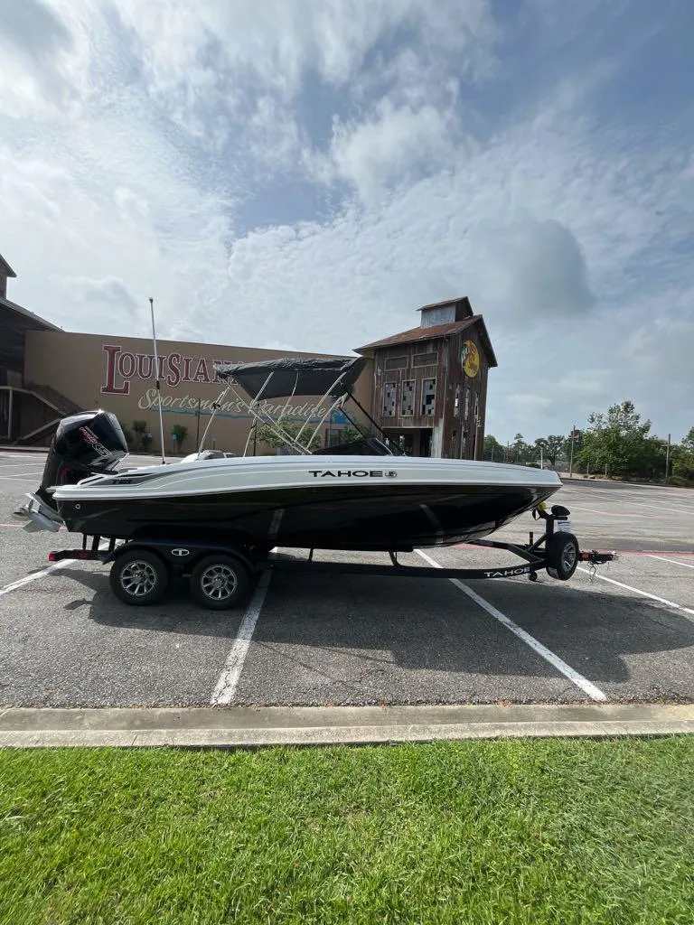Slide: The Image of 2025 Tahoe T21 boat on trailer in parking lot, cloudy sky background. - 5