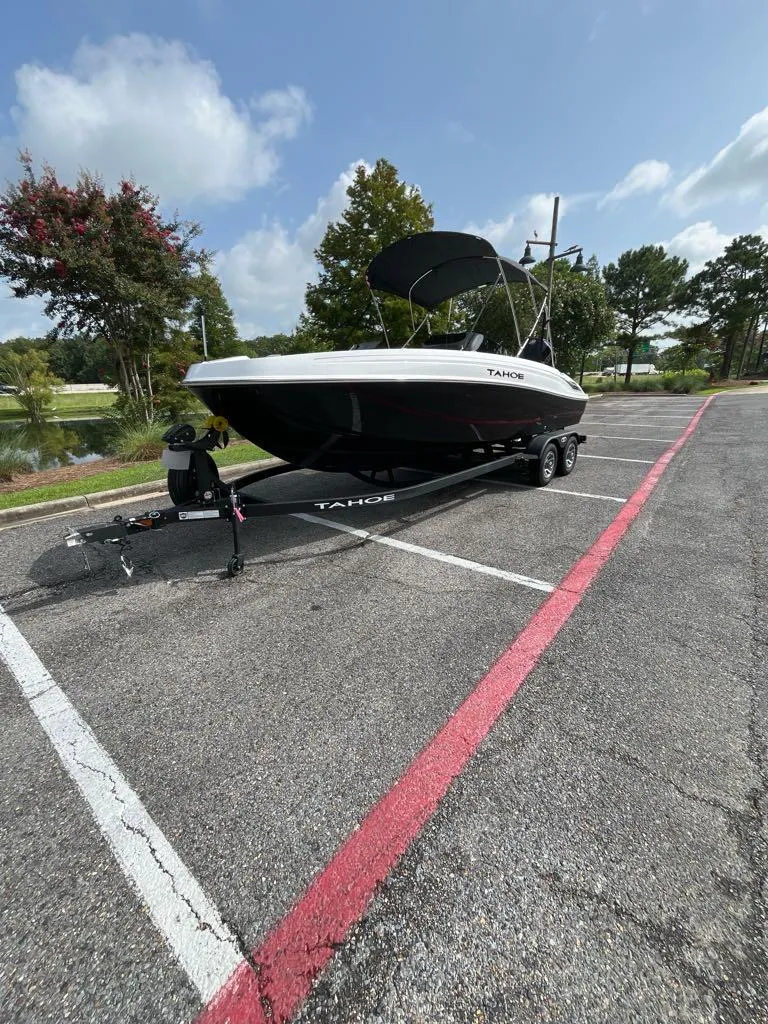 Slide: The Image of 2025 Tahoe T21 boat on trailer in parking lot, sunny day, trees in background. - 8