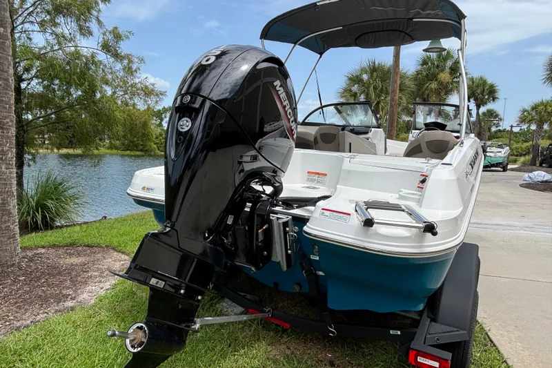 Slide: The Image of 2025 Tahoe 200 S boat with Mercury outboard motor, parked near a scenic lake. - 3