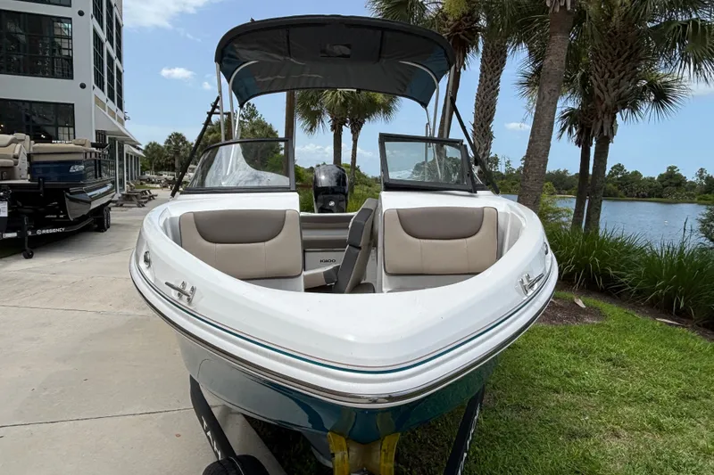 Slide: The Image of 2025 Tahoe 200 S boat docked near palm trees and a lake. - 1