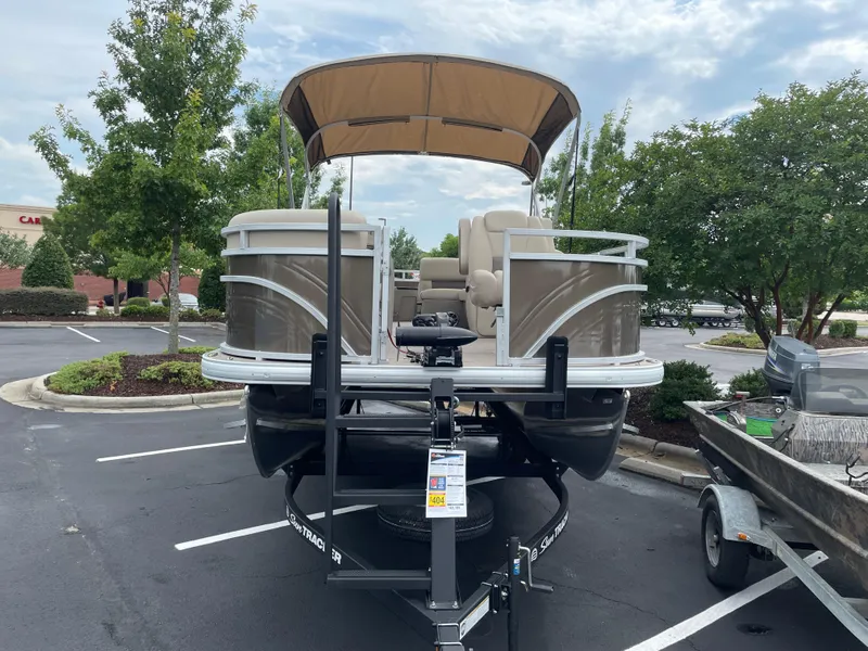 Slide: The Image of 2025 Sun Tracker SportFish 20 DLX pontoon boat parked in a lot with trees. - 2