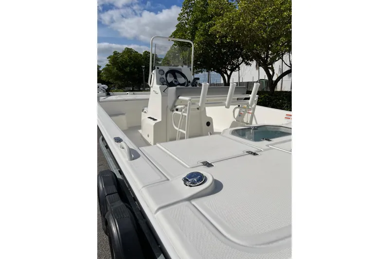 Slide: The Image of 2024 Mako Pro Skiff 19 CC boat, white deck, center console, sunny day, trees in background. - 5