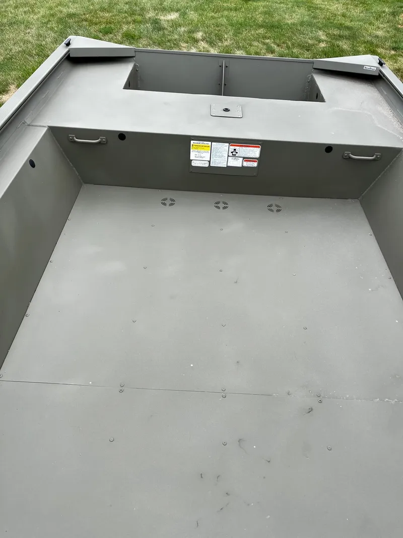 Slide: The Image of 2025 Tracker GRIZZLY 1860 Utility boat interior, featuring spacious, durable design on grassy background. - 2