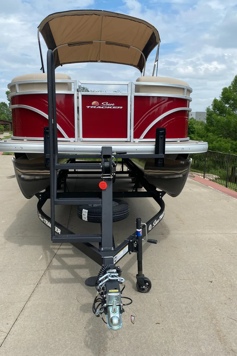 Slide: The Image of 2025 Sun Tracker Party Barge 22 DLX on trailer, red exterior, parked outdoors. - 2