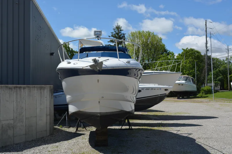 Slide: The Image of 2004 Crownline 270 CR boat on dry dock, surrounded by trees and other boats. - 11