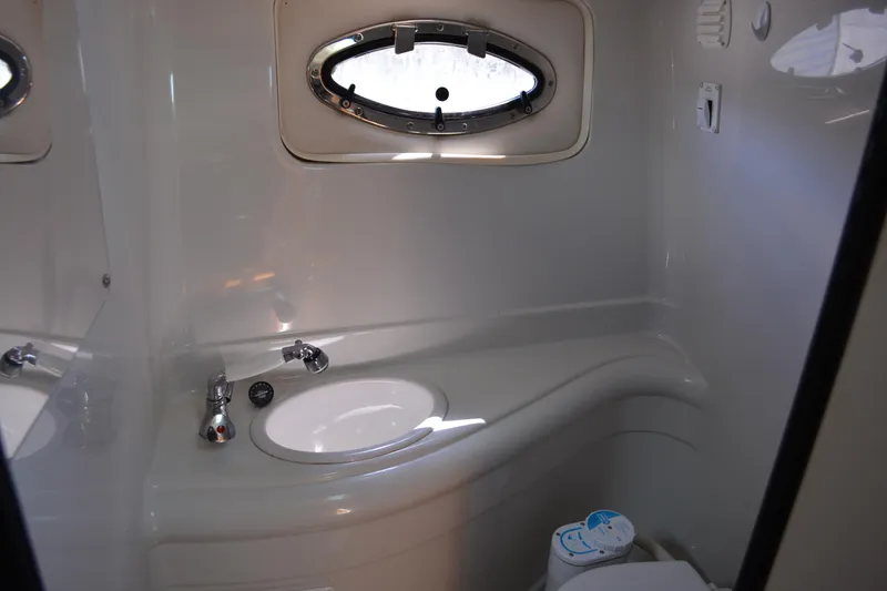 Slide: The Image of 2004 Crownline 270 CR boat bathroom with sink, toilet, and porthole window. - 28