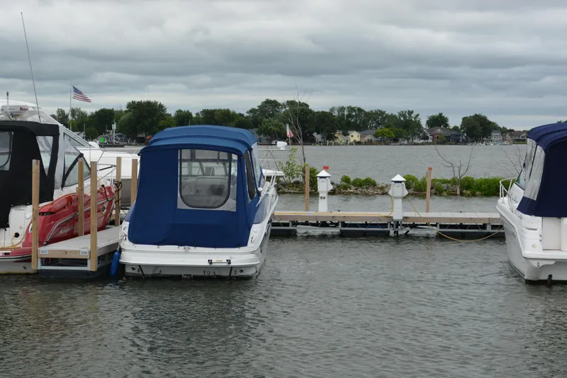 Slide: The Image of 2004 Crownline 270 CR boat docked at marina with blue cover, cloudy sky. - 3