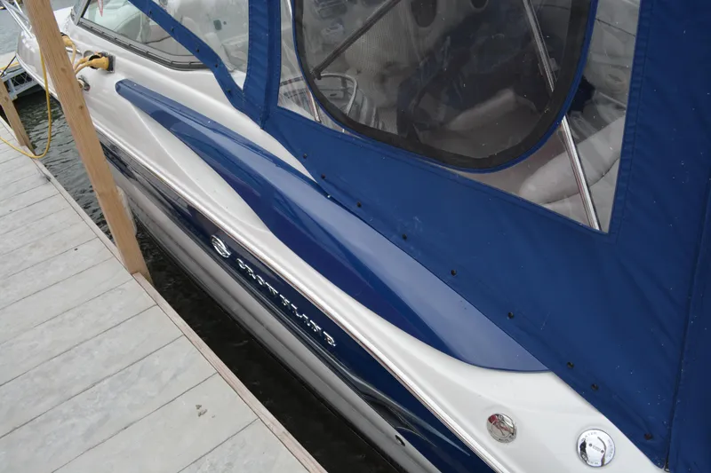 Slide: The Image of 2004 Crownline 270 CR boat docked with blue canopy and sleek design. - 4