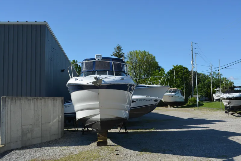 Slide: The Image of 2004 Crownline 270 CR boat on dry dock near a metal building, surrounded by other boats. - 7