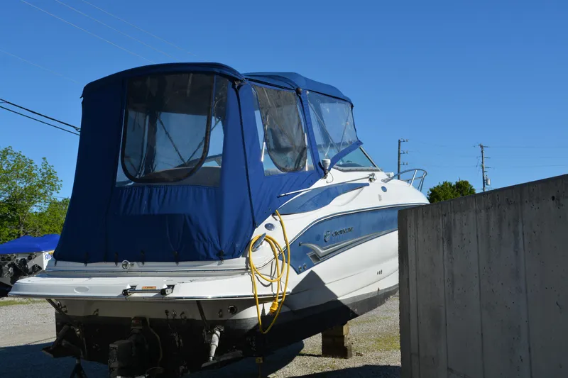Slide: The Image of 2004 Crownline 270 CR boat with blue canopy, parked on gravel under clear sky. - 9