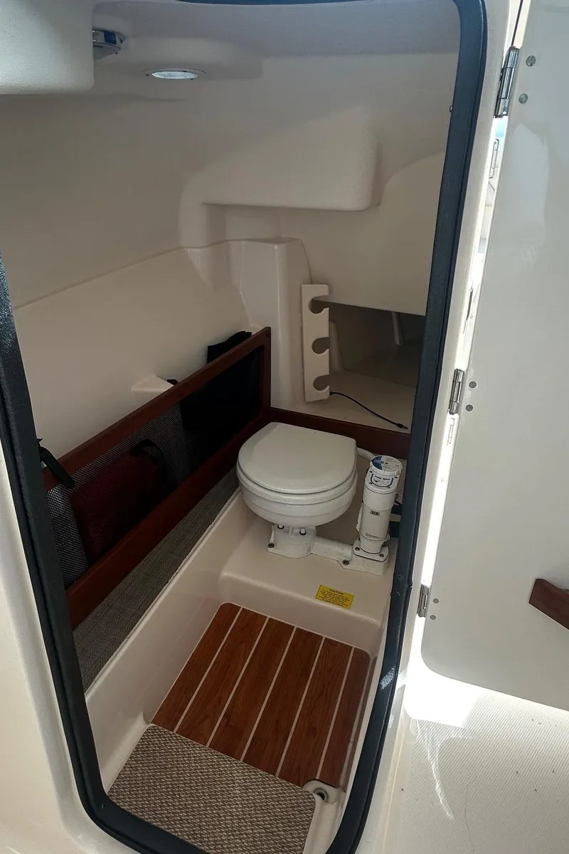 Slide: The Image of 2017 Grady-White Freedom 275 boat interior with compact marine toilet and wooden flooring. - 10