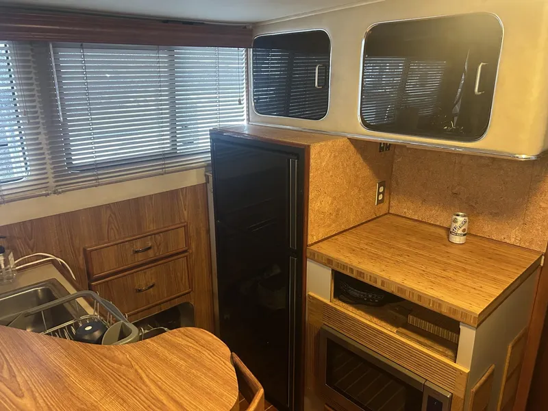 Slide: The Image of 1988 Chris-Craft 381 Catalina interior kitchen with wood cabinets, blinds, and countertop. - 19