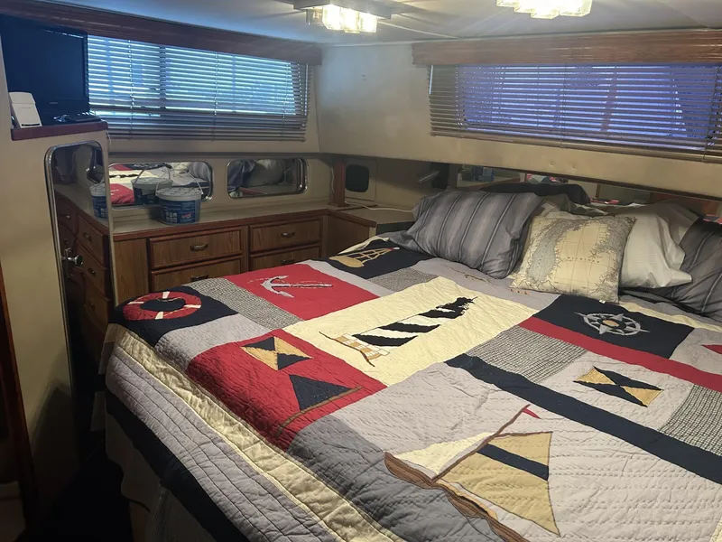 Slide: The Image of 1988 Chris-Craft 381 Catalina bedroom with nautical-themed quilt and wooden cabinetry. - 21