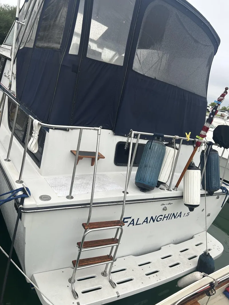 Slide: The Image of 1988 Chris-Craft 381 Catalina boat with blue canopy and docked fenders. - 23