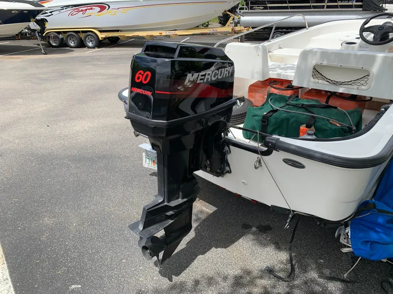 Slide: The Image of 2005 Boston Whaler 150 Sport with Mercury 60 outboard motor, parked on pavement. - 6