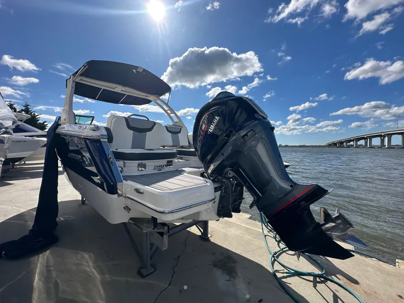 Slide: The Image of 2023 Chaparral 250 OSX boat docked by the water under a sunny sky. - 12