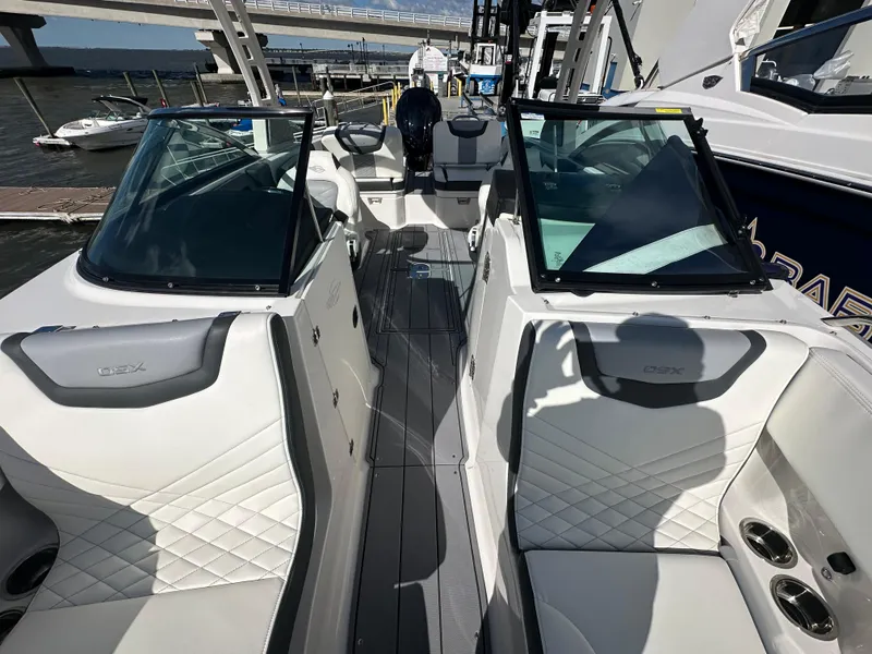 Slide: The Image of 2023 Chaparral 250 OSX boat interior with white seating, docked by the water. - 17