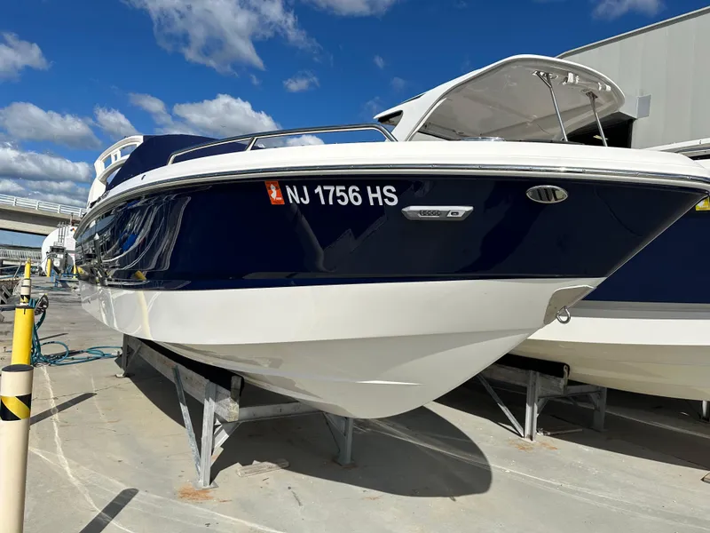 Slide: The Image of 2023 Chaparral 250 OSX boat on display, blue and white hull, sunny day. - 2